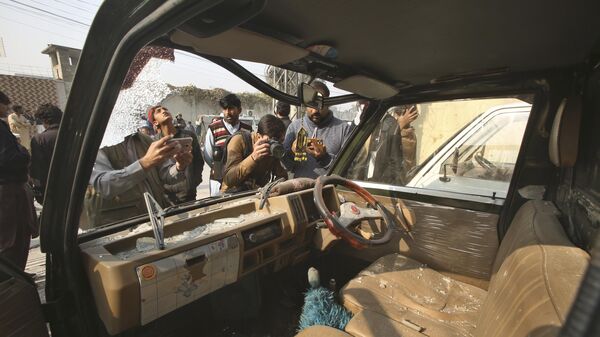 Представители СМИ снимают поврежденный автомобиль на месте взрыва бомбы в Пешаваре, Пакистан - Sputnik Грузия