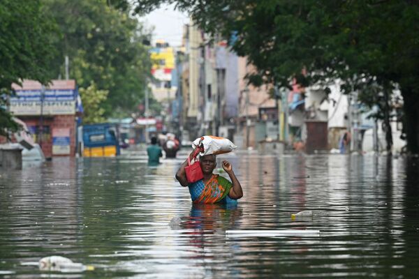 Женщина вместе со своими вещами идет по затопленной улице после проливных дождей в Индии. - Sputnik Грузия