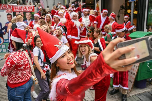 Девушки делают селфи во время ежегодного парада SantaCon в Гонконге. - Sololaki Грузия