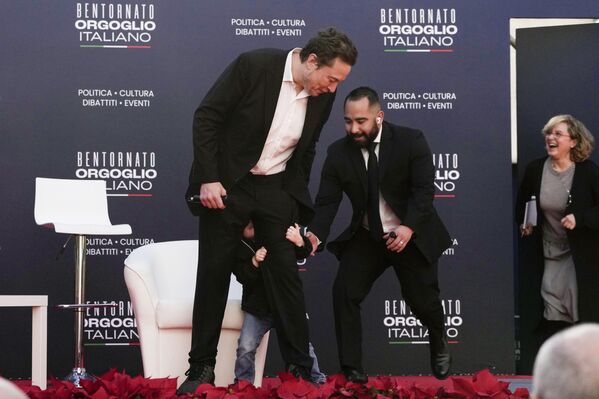 Охранник помогает за кулисами сыну генерального директора Tesla и SpaceX Илона Маска, обнимающему ногу своего отца. - Sputnik Грузия