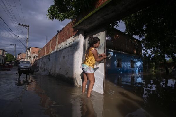 Женщина закрывает ворота своего затопленного дома после проливного дождя. - Sputnik Грузия