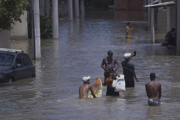 Люди идут по затопленной улице после проливного дождя в Бразилии. - Sputnik Грузия
