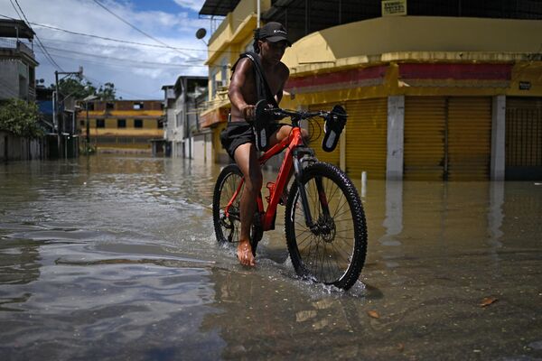 Мужчина на велосипеде движется по затопленной улице в поселении Лоте XV. - Sputnik Грузия