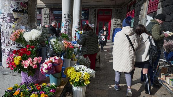 Девушки идут мимо торговца цветами на улице - Sputnik Грузия