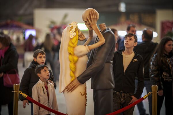 Люди смотрят на инсталляцию целующейся пары скелетов в Бухаресте. - Sputnik Грузия
