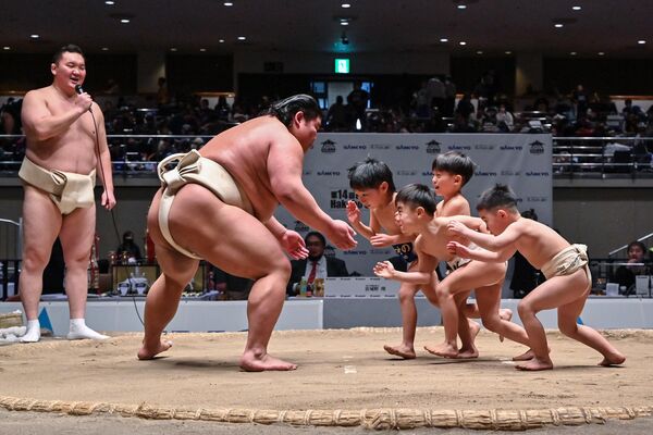 Юные спортсмены пытаются вытеснить с дохё японского борца Хакуохо во время занятия сумо. - Sputnik Грузия