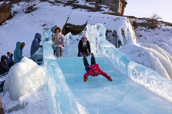 Посетители катаются на горке на фестивале ледовых скульптур &quot;Olkhon Ice Park&quot;. - Sputnik Грузия