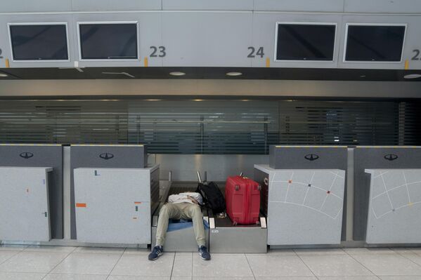 Пассажир отдыхает в зоне регистрации после задержки вылета в аэропорту в Буэнос-Айресе. - Sputnik Грузия