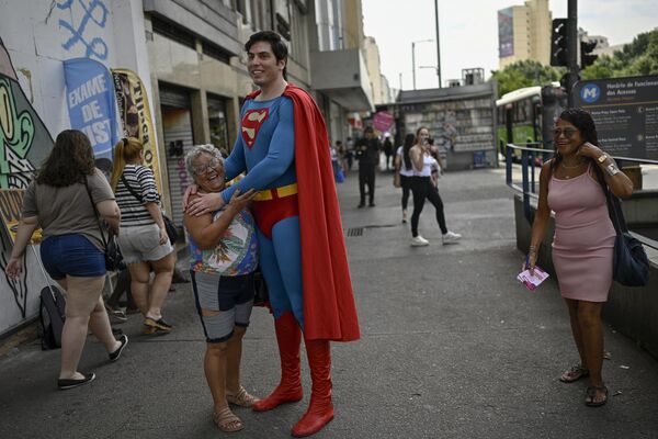 Леонардо Муйлаерт, известный как Бразильский Супермен, позирует для фотографии с женщиной на площади Санс Пенья в Рио-де-Жанейро. - Sputnik Грузия