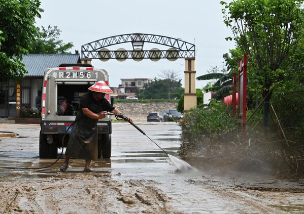 Рабочий убирает грязь с дороги после того, как проливные дожди затопили территорию в Цинъюань в северной провинции Гуандун. - Sputnik Грузия