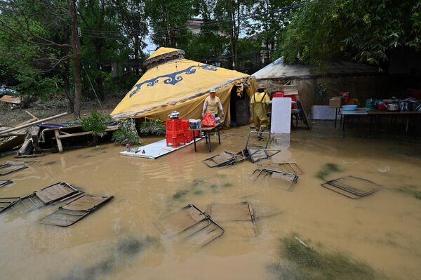 Рабочий собирает вещи после того, как проливные дожди затопили территорию в Цинъюань в северной провинции Гуандун в Китае. - Sputnik Грузия