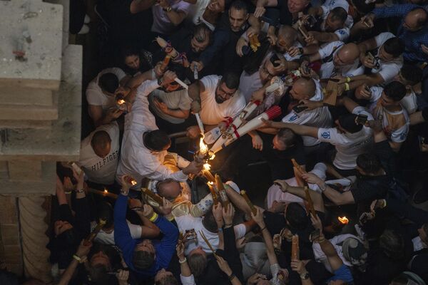 Греческий православный патриарх Иерусалима Феофил III держит свечи для христианских паломников во время церемонии зажжения Благодатного огня. - Sputnik Грузия