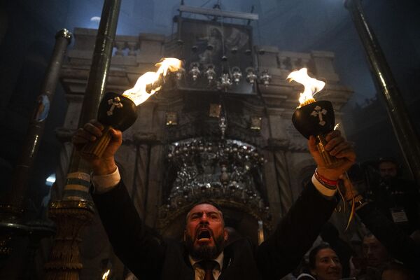 Христианин с зажженными свечами во время церемонии Благодатного огня в храме Гроба Господня в Иерусалиме. - Sputnik Грузия