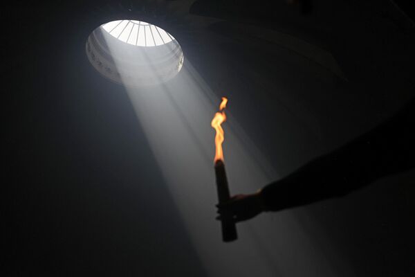 Православный христианин держит зажженную свечу в храме Гроба Господня. - Sputnik Грузия