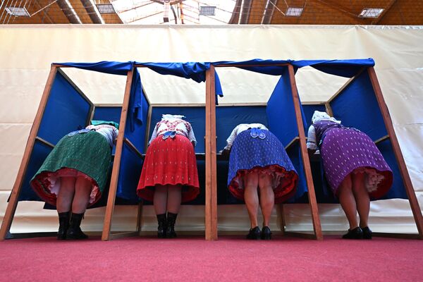 Женщины в традиционных венгерских платьях заполняют свои бюллетени на избирательном участке в Венгрии. - Sputnik Грузия