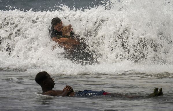 Мужчина и его собака прислонились к дамбе Малекон, играя в воде, которая падает на тротуар из-за урагана &quot;Милтон&quot;, проходящего через Мексиканский залив. - Sputnik Грузия