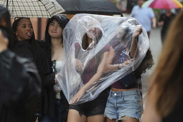Девушки используют полиэтиленовый пакет, прогуливаясь под дождём в Старом городе Таллина. - Sputnik Грузия
