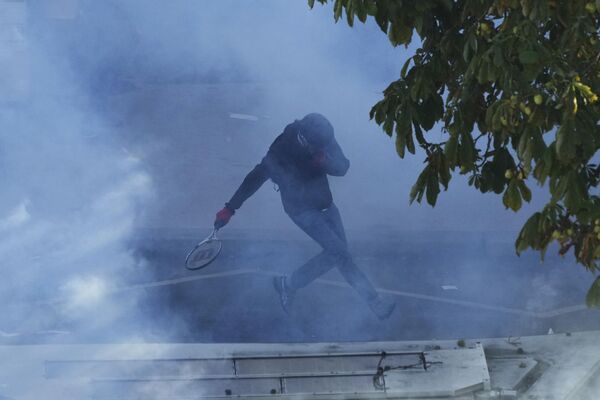 Протестующий бежит от слезоточивого газа во время демонстрации. - Sputnik Грузия