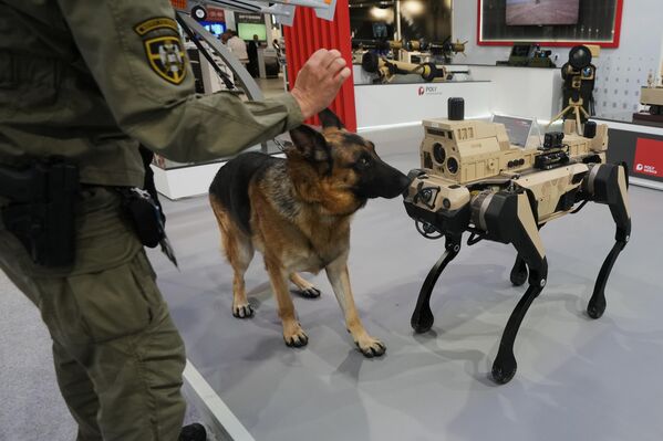 Сербская армейская служебная собака осматривает разведывательно-ударного четвероногого робота на выставке вооружений в Белграде. - Sputnik Грузия