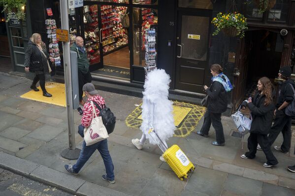 Смешно одетый человек везет жёлтый чемодан по Лондону. Смешно одетый человек везет жёлтый чемодан по Лондону. - Sputnik Грузия