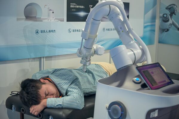 Посетитель тестирует массажного робота на отраслевом саммите по гуманоидным роботам в Китае. Посетитель тестирует массажного робота на отраслевом саммите по гуманоидным роботам в Китае. - Sputnik Грузия