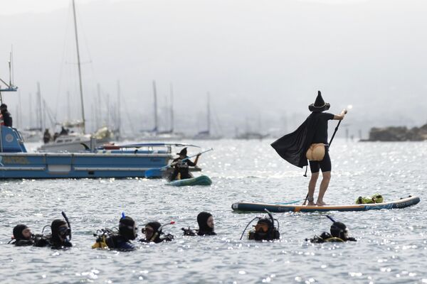 Аквалангисты наблюдают за гребцом, одетым в костюм, во время ежегодного фестиваля ведьм и колдунов в США. - Sputnik Грузия