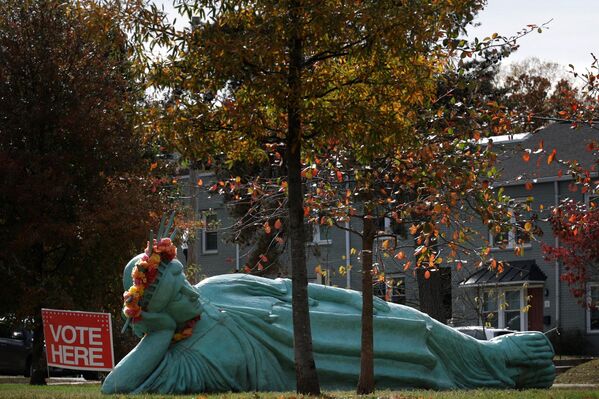 Табличка &quot;Голосуйте здесь&quot; около лежащей Статуи Свободы ​​перед избирательным участком в Арлингтоне, штат Вирджиния. - Sputnik Грузия