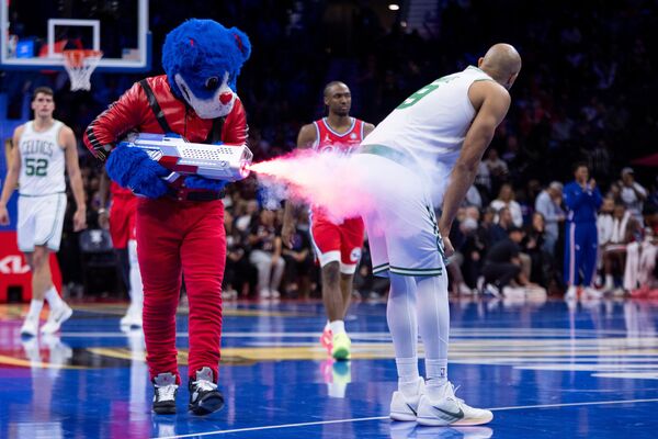 Талисман Philadelphia 76ers, одетый в костюм Майкла Джексона из фильма &quot;Триллер&quot;, выстреливает из бутафорского пистолета в Деррика Уайта из &quot;Бостон Селтикс&quot; на баскетбольном матче Кубка НБА. - Sputnik Грузия