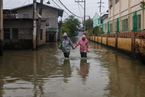 Семейная пара идет по затопленной улице в Булакане. - Sputnik Грузия