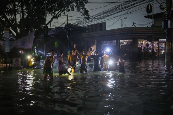 Молодые люди на затопленной улице во время супертайфуна Фунг-Вонг в Маниле. - Sputnik Грузия