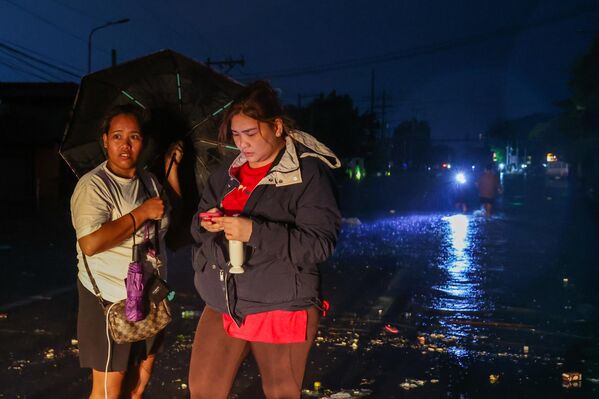 Женщины ждут, пока спадет вода в затопленном районе, где произошло отключение электроэнергии во время супертайфуна Фунг-Вонг в Маниле. - Sputnik Грузия