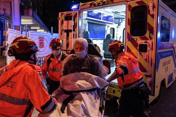 Пострадавшего кладут в машину скорой помощи после пожара в жилом комплексе в Гонконге. - Sputnik Грузия