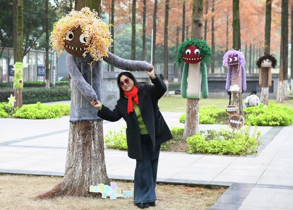 Житель города позирует для фотографии на фоне деревьев, украшенных разноцветными свитерами в Чунцине, Китай. Житель города позирует для фотографии на фоне деревьев, украшенных разноцветными свитерами в Чунцине, Китай. - Sputnik Грузия