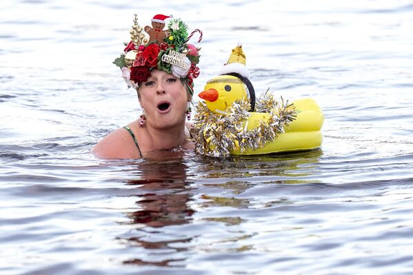  Loch Insh Dippers-ის მონაწილე ლოხ-ინშის ტბაში საახალწლოდ მორთული ქუდით ცურავს, შოტლანდია, კერნგორმსის ეროვნული პარკი. - Sputnik საქართველო