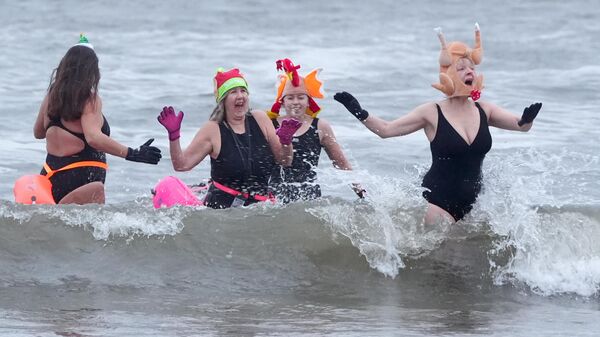 Люди купаются в заливе Каллеркотс в Северном Тайнсайде в канун Рождества, Великобритания - Sputnik Грузия