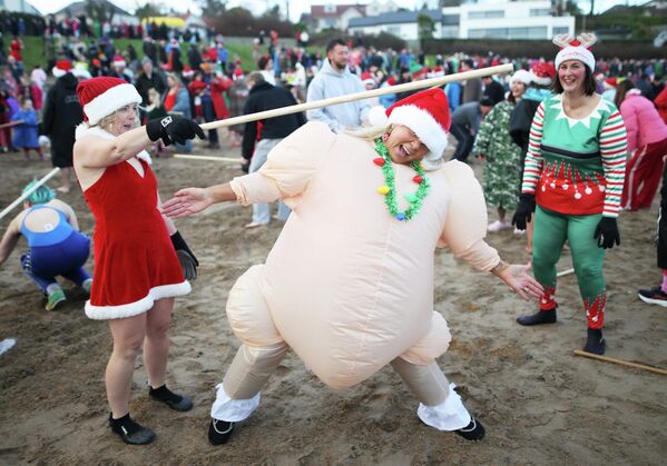  ხალხი ზღვაში შესვლამდე პლაჟზე თბება, ჩრდილოეთ ირლანდია. - Sputnik საქართველო