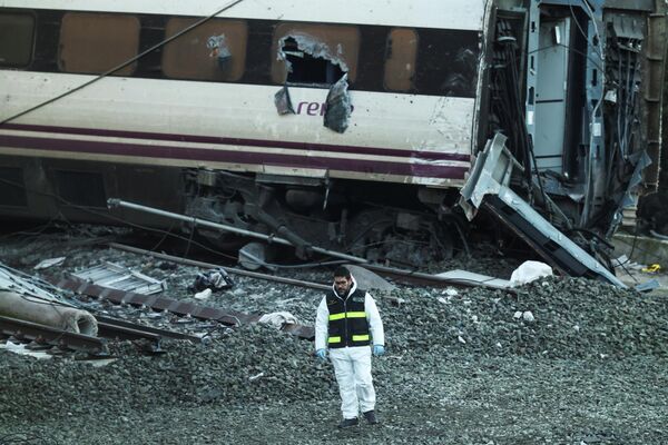 Сотрудник испанской гражданской гвардии стоит рядом с обломками на месте схода с рельсов 20 января 2026 года двух высокоскоростных поездов недалеко от Адамуса, Испания.  - Sputnik Грузия