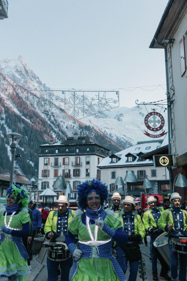 Танцоры и музыканты проходят парадом по заснеженным улицам Шамони во Франции. - Sputnik Грузия