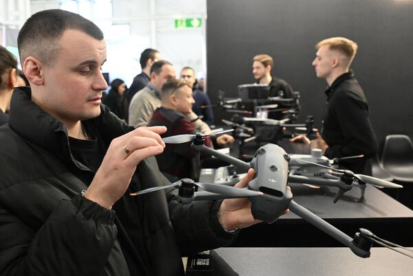 Посетитель держит квадрокоптер DJI. - Sputnik Грузия