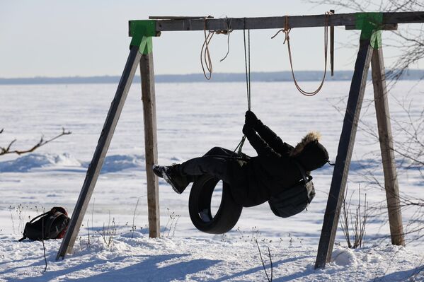 Мальчик качается на качелях на берегу замерзшего Финского залива в Санкт-Петербурге.  - Sputnik Грузия