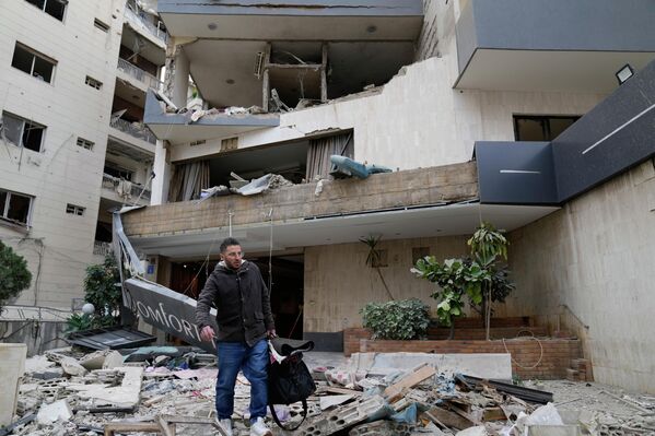 Мужчина с вещами покидает поврежденный израильским авиаударом отель в Хазмие, к востоку от Бейрута, Ливан. - Sputnik Грузия