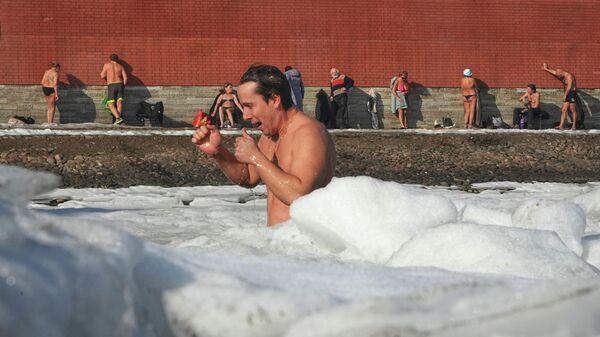 Мужчина плавает в ледяной воде, в то время как другие загорают у стен Петропавловской крепости в Санкт-Петербурге, Россия - Sputnik Грузия