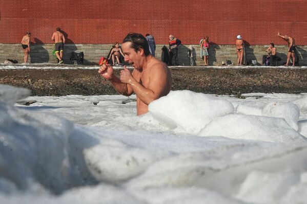 Мужчина плавает в ледяной воде, в то время как другие загорают у стен Петропавловской крепости в Санкт-Петербурге. Мужчина плавает в ледяной воде, в то время как другие загорают у стен Петропавловской крепости в Санкт-Петербурге. - Sputnik Грузия