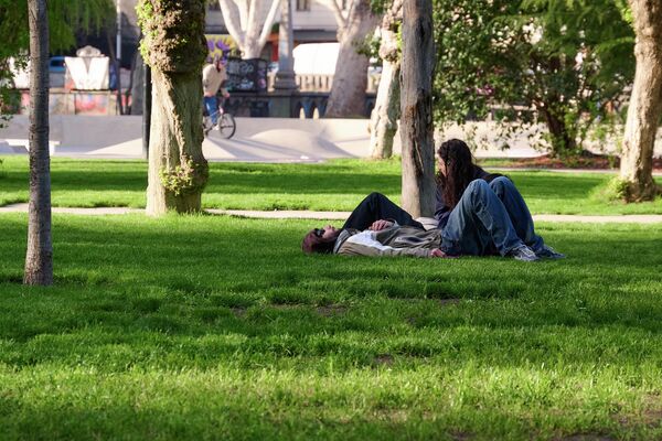 Даже в будни, в разгар рабочего дня в парке Дэда Эна на набережной Тбилиси люди отдыхают на лужайках в лучах солнца. - Sputnik Грузия