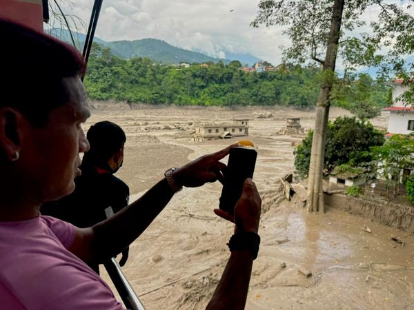 Люди фотографируют и снимают на видео разлившиеся, заваленные обломками берега реки Тришули после внезапного наводнения в районе Нувакот в Непале. - Sputnik Грузия