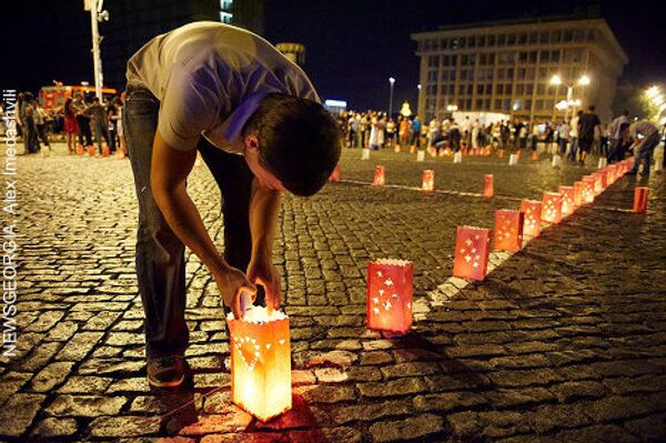 Участник акции зажигает свечи на площади Роз, в память о погибших в августе 2008 года. - Sputnik Грузия