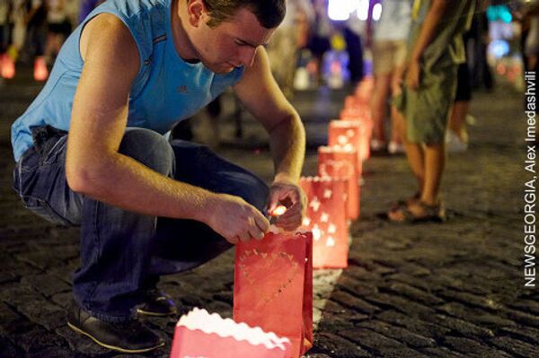 Участник акции зажигает свечи на площади Роз, в рамках акции памяти по погибшим в августе 2008 года. - Sputnik Грузия