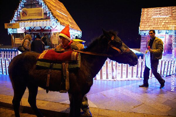 Скучающий Дед Мороз в новогоднем городке ждет клиентов, желающих прокатиться на лошади. - Sputnik Грузия