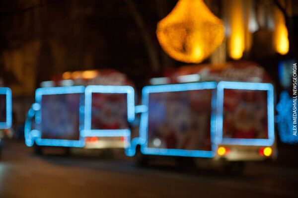 Традиционно под Новый год Тбилиси объезжают украшенные разноцветными огнями машины компании Кока Кола, на которых установлены динамики, из которых звучат новогодние поздравления и праздничная музыка. - Sputnik Грузия