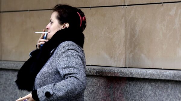 Женщина курит на одной из улиц Москвы. - Sputnik Грузия